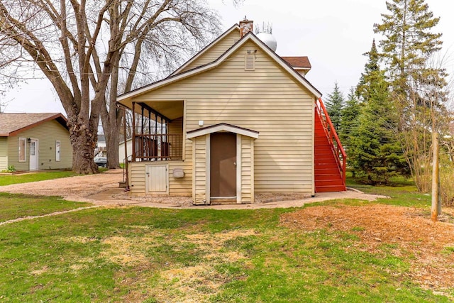 bungalow featuring stairway, a chimney, and a front yard