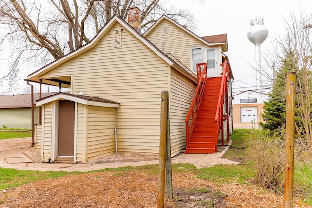 back of house featuring a chimney and stairs