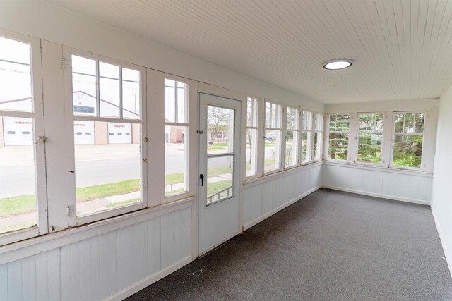 unfurnished sunroom featuring wood ceiling and carpet