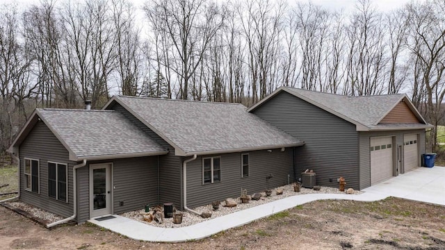 view of side of property featuring roof with shingles and an attached garage