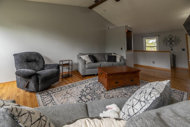 living area with baseboards, a ceiling fan, lofted ceiling with beams, and wood finished floors