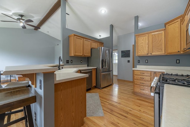 kitchen with a ceiling fan, a peninsula, vaulted ceiling with beams, a sink, and appliances with stainless steel finishes