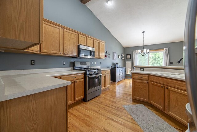 kitchen featuring an inviting chandelier, pendant lighting, light countertops, light wood-style flooring, and stainless steel appliances