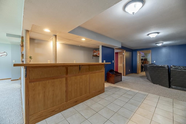 kitchen featuring a textured ceiling, baseboards, open floor plan, light carpet, and light tile patterned flooring