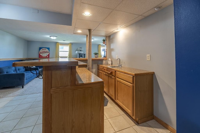 bar featuring indoor wet bar, a drop ceiling, recessed lighting, a sink, and light tile patterned floors