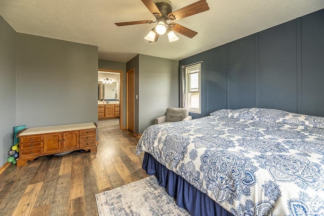 bedroom featuring connected bathroom, a ceiling fan, baseboards, and dark wood-style floors