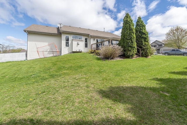 back of property with a yard, a deck, and fence