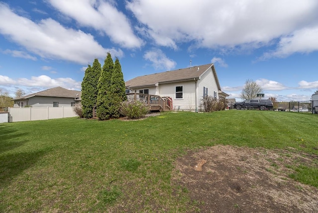 back of house featuring fence, a wooden deck, and a yard