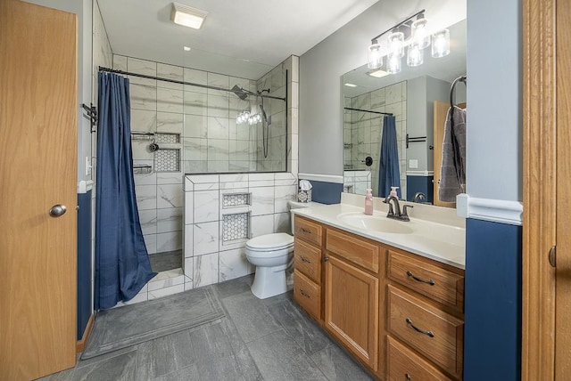 full bath featuring vanity, a tile shower, and toilet