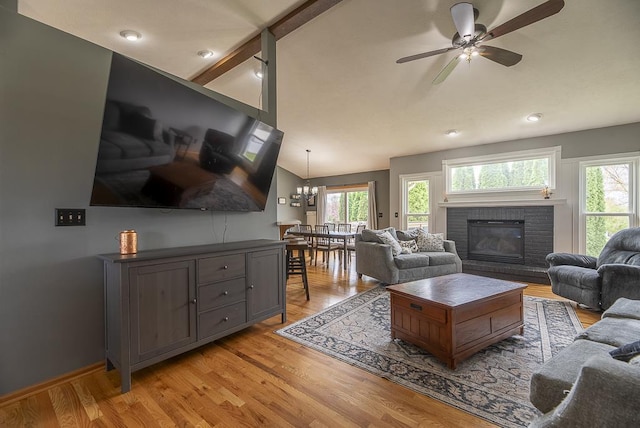 living room with a brick fireplace, light wood-style floors, recessed lighting, ceiling fan with notable chandelier, and vaulted ceiling