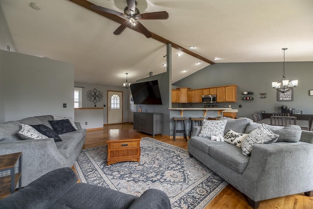 living room featuring ceiling fan with notable chandelier, lofted ceiling, and light wood-type flooring