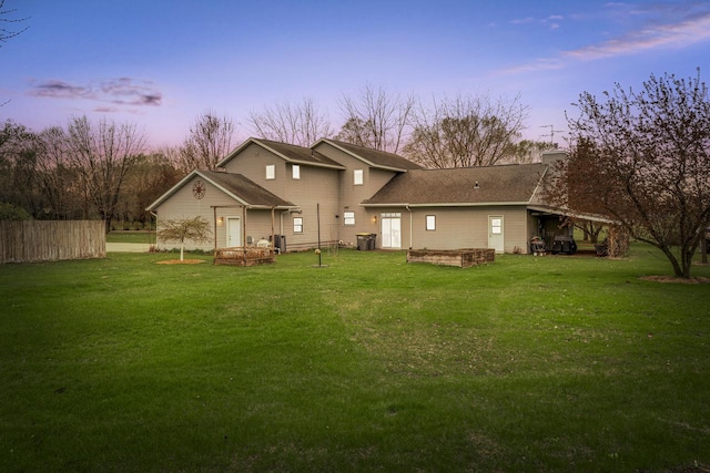 back of property featuring fence, a yard, and a chimney