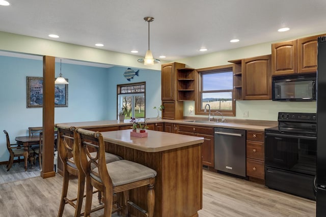 kitchen with open shelves, light wood-style flooring, a sink, a breakfast bar, and black appliances
