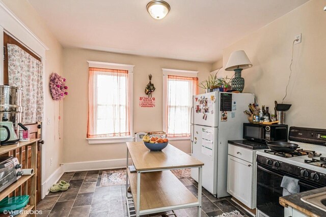 2968 N Buffum St Unit 2968A, Milwaukee, WI 53212 - kitchen with black microwave, range with gas cooktop, stone finish floor, baseboards, and freestanding refrigerator