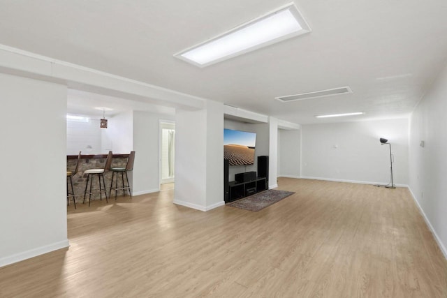 unfurnished living room with baseboards, a dry bar, and wood finished floors