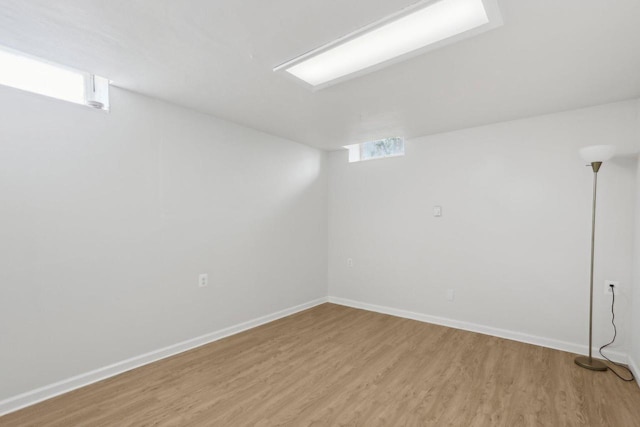 below grade area featuring baseboards, plenty of natural light, and light wood finished floors