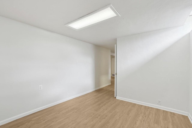 spare room featuring baseboards and light wood-type flooring