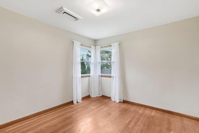 empty room featuring baseboards, visible vents, and light wood-style floors