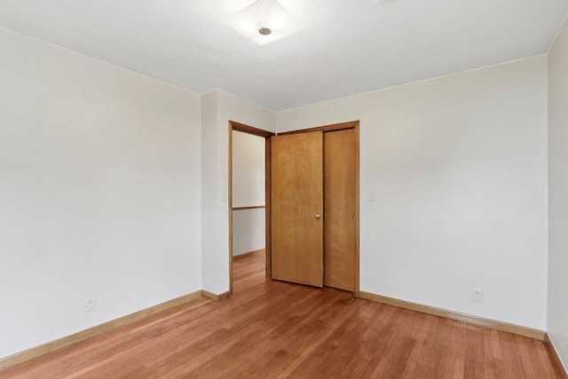 unfurnished bedroom featuring baseboards, light wood-style floors, and a closet