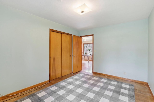 unfurnished bedroom with a closet, light wood-style flooring, and baseboards