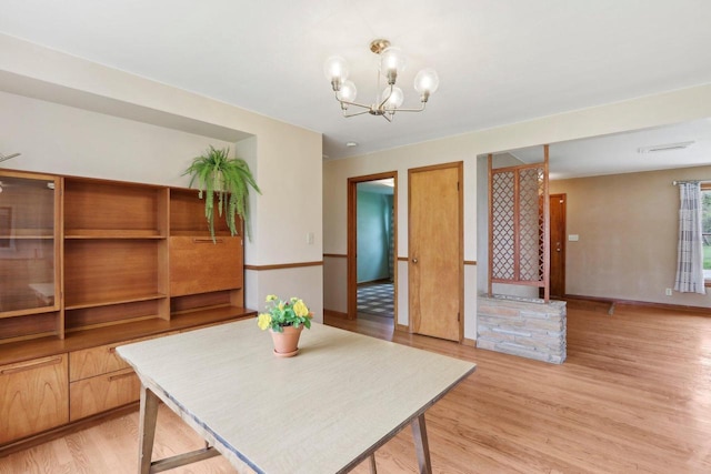 unfurnished dining area with an inviting chandelier, baseboards, and light wood-style flooring