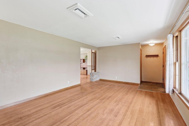 empty room featuring baseboards, visible vents, and light wood finished floors