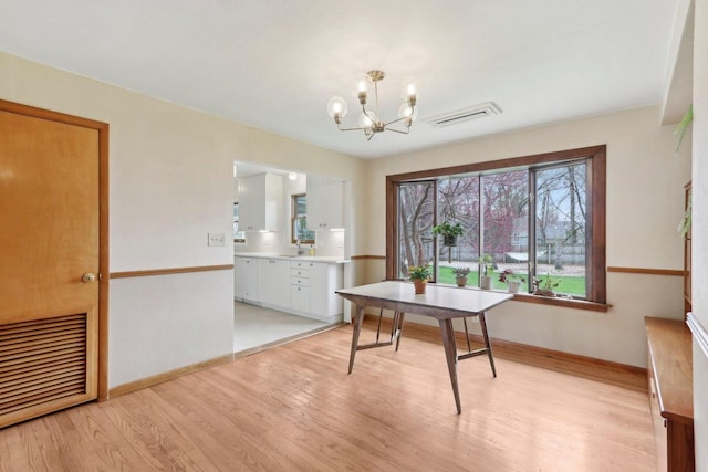 dining space with baseboards, visible vents, light wood-style flooring, and a chandelier