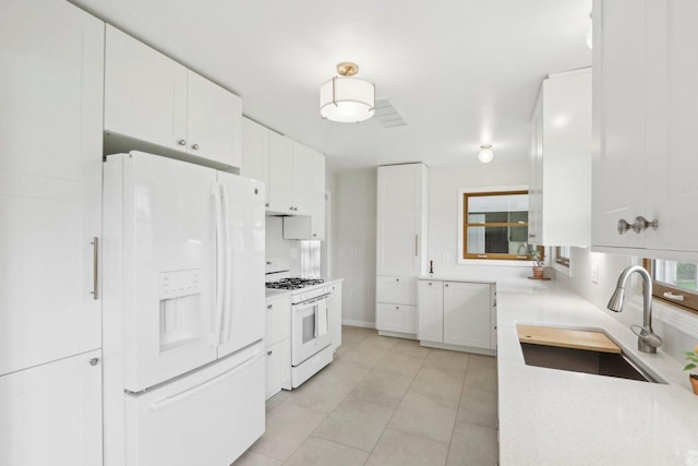 kitchen with light tile patterned flooring, white appliances, light countertops, white cabinets, and a sink