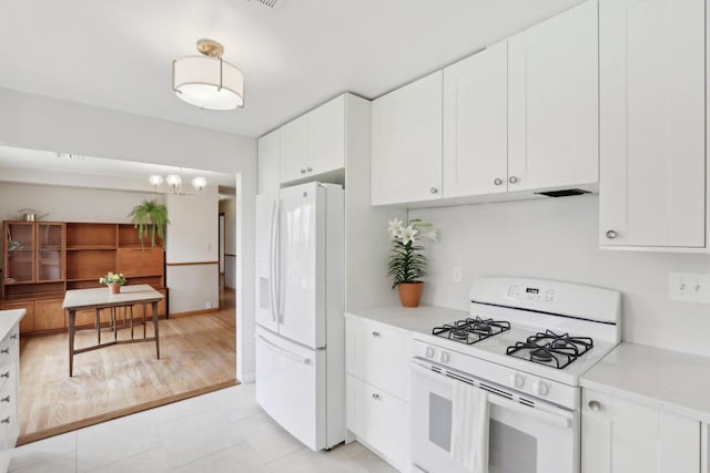 kitchen with light countertops, white cabinetry, a chandelier, and white appliances