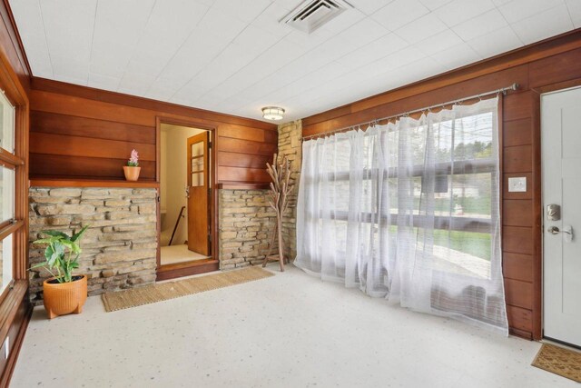 unfurnished living room featuring wooden walls and visible vents
