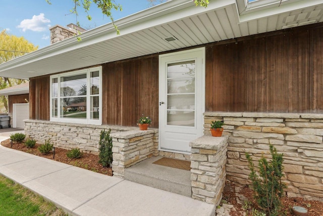 view of exterior entry with a chimney and stone siding