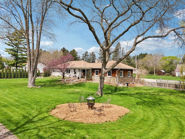 view of front of house featuring fence, a fire pit, a front lawn, and stone siding