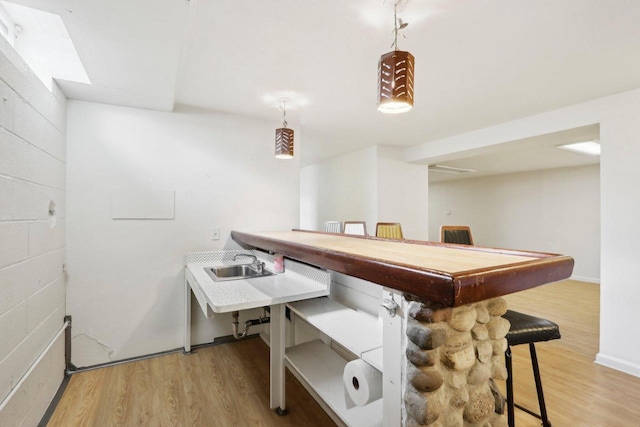 game room featuring a sink, concrete block wall, and light wood finished floors
