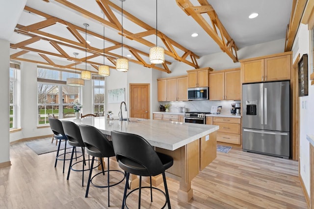 kitchen with light brown cabinets, lofted ceiling with beams, tasteful backsplash, a sink, and stainless steel appliances