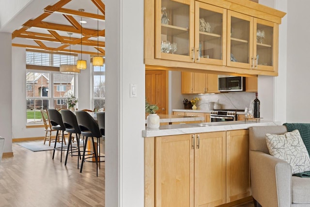 bar featuring backsplash, appliances with stainless steel finishes, wood finished floors, baseboards, and beamed ceiling