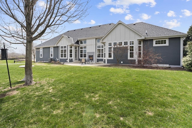 rear view of house featuring a shingled roof, board and batten siding, a patio area, and a yard