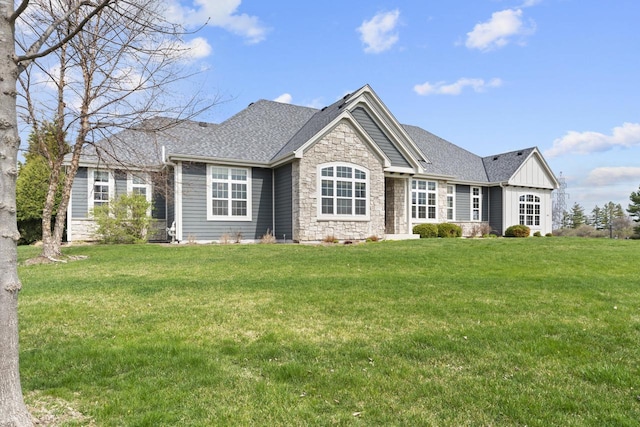 view of front of property with board and batten siding, roof with shingles, stone siding, and a front lawn