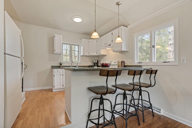 805 Manor Dr, Twin Lakes, WI 53181 - kitchen featuring dark countertops, white cabinets, freestanding refrigerator, a peninsula, and light wood finished floors