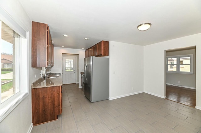 kitchen with light stone counters, a sink, visible vents, recessed lighting, and stainless steel fridge with ice dispenser
