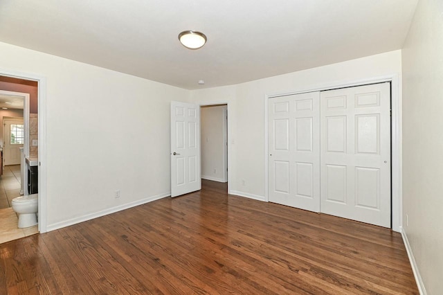 unfurnished bedroom featuring wood finished floors, connected bathroom, a closet, and baseboards