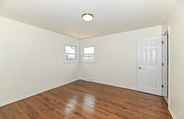 unfurnished room featuring visible vents, wood finished floors, and baseboards