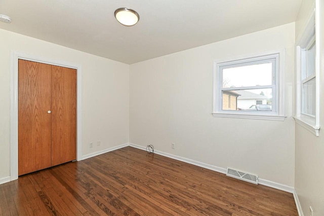unfurnished bedroom featuring a closet, visible vents, wood finished floors, and baseboards