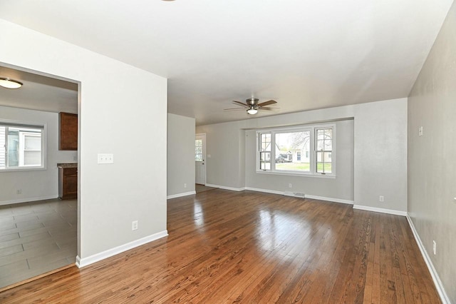 unfurnished living room featuring baseboards, visible vents, hardwood / wood-style flooring, and ceiling fan