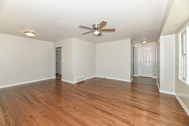 unfurnished room with visible vents, ceiling fan, wood finished floors, and baseboards