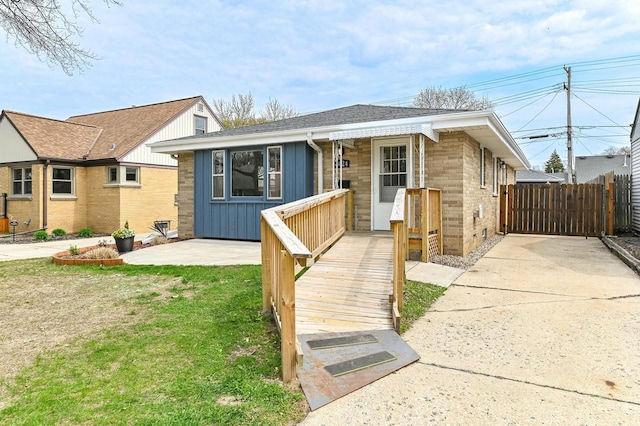 bungalow with brick siding, fence, board and batten siding, and a front yard