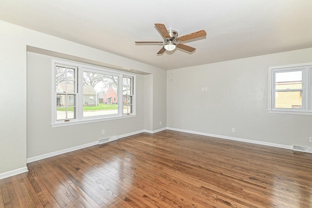 unfurnished room featuring wood-type flooring, a ceiling fan, visible vents, and baseboards