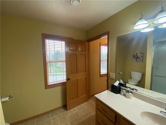 full bath featuring toilet, baseboards, vanity, and plenty of natural light