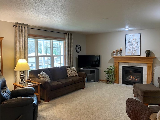 living area with a tiled fireplace, carpet floors, and a textured ceiling