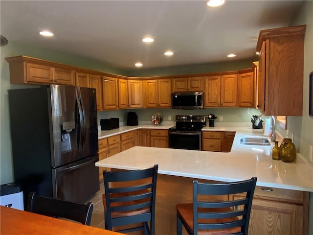 kitchen with a sink, appliances with stainless steel finishes, light countertops, recessed lighting, and a peninsula