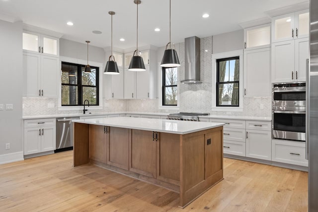 N1931 Linn Rd, Lake Geneva, WI 53147 - kitchen with a kitchen island, wall chimney range hood, light countertops, tasteful backsplash, and stainless steel appliances